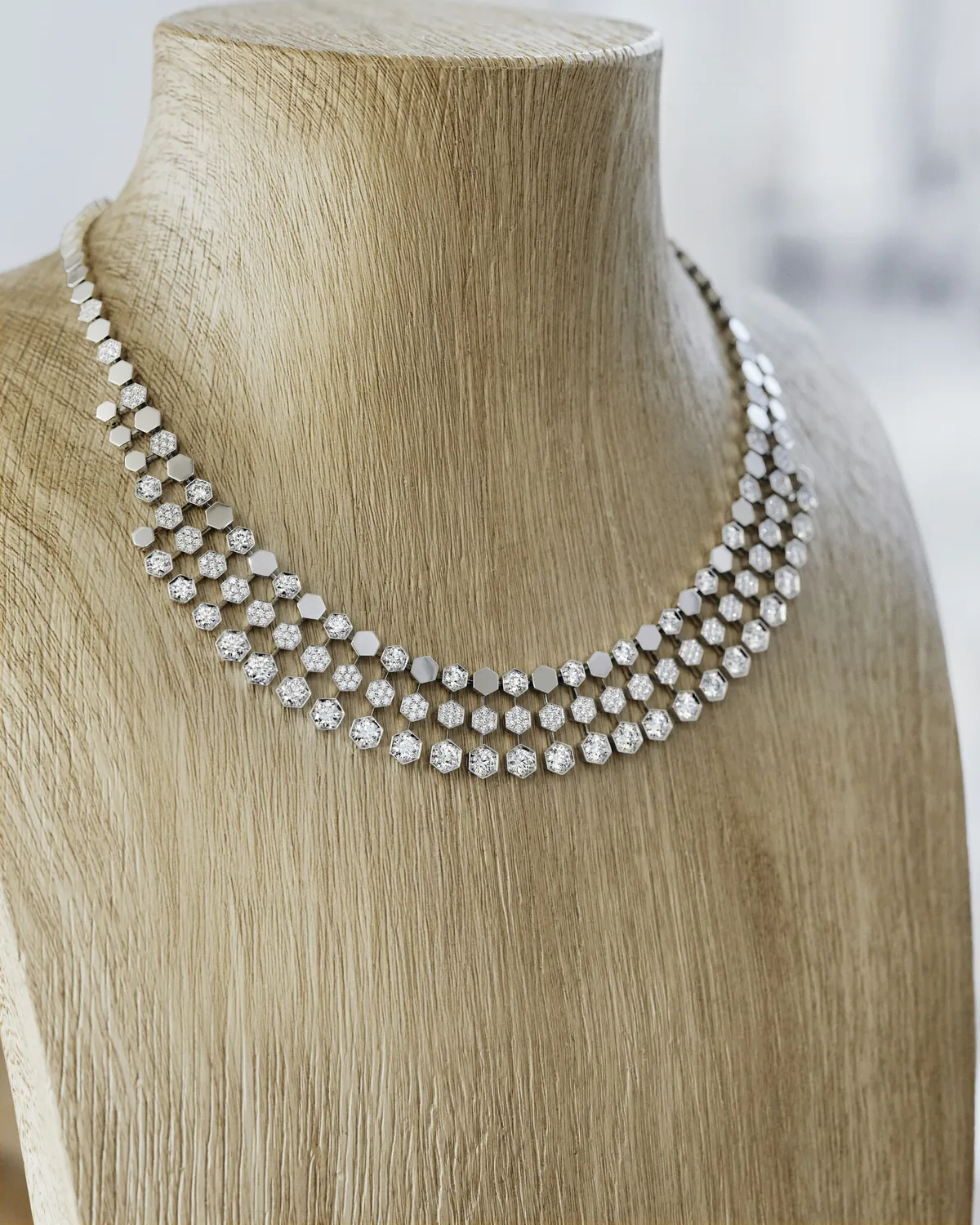 Collier plastron Bee de Chaumet en or et diamants présenté sur un buste en bois clair