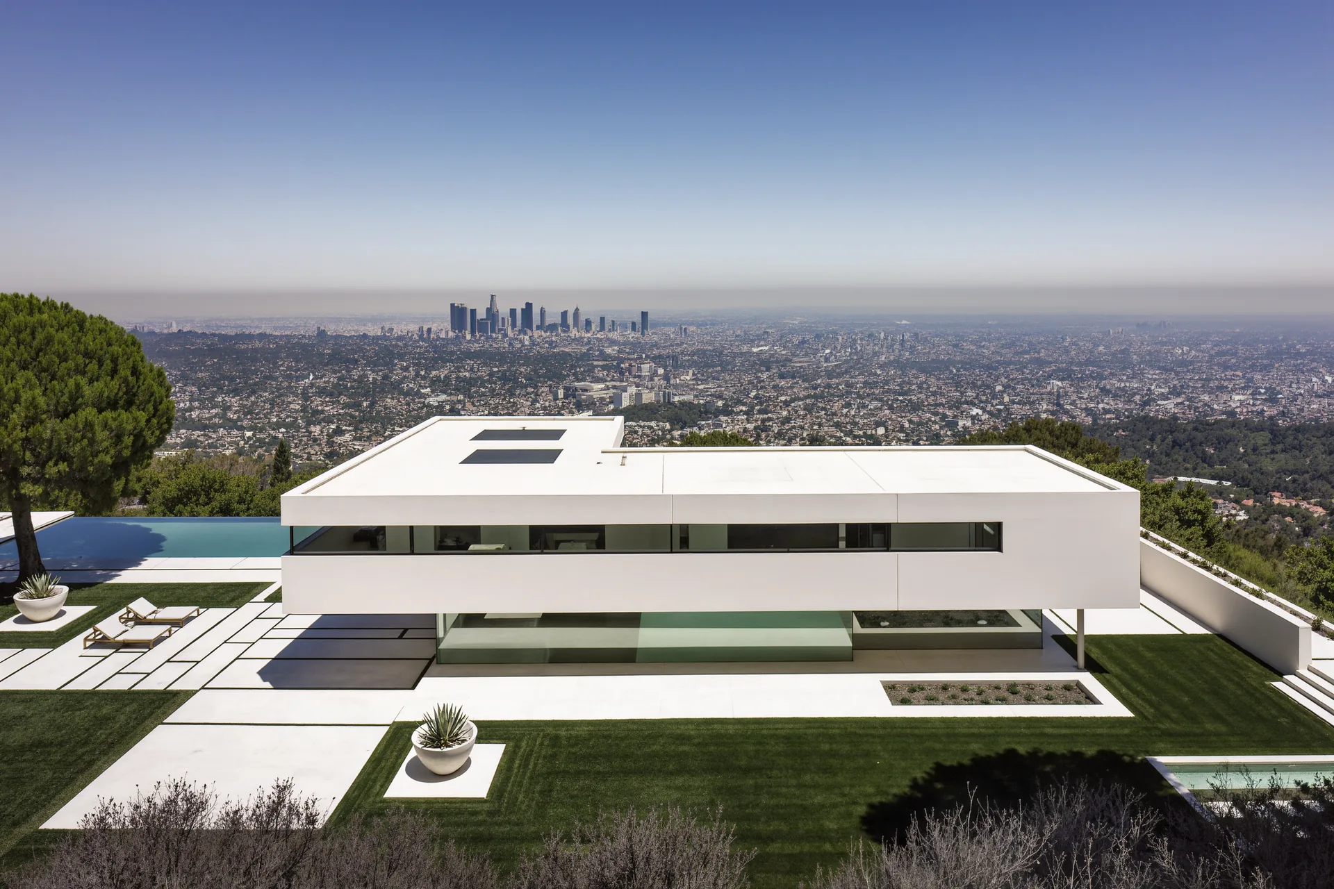 Villa moderniste blanche sur pilotis, longues baies horizontales et toit-terrasse épuré