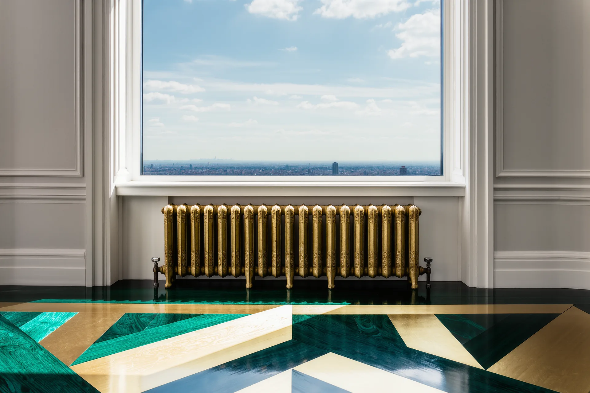 Radiateur en fonte ancien sous une haute fenêtre d'une demeure, parquet ciré et moulures blanches