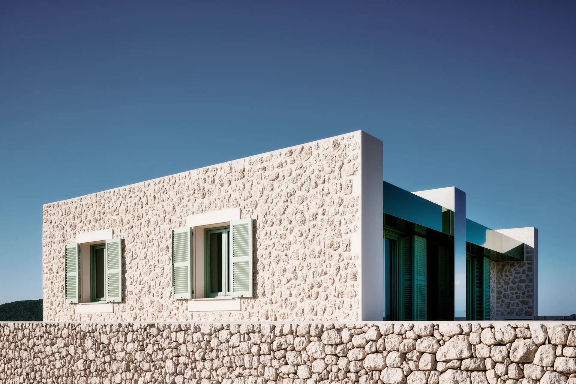 Mas provençal en pierre sèche sous un ciel bleu, façade sud percée de volets clairs