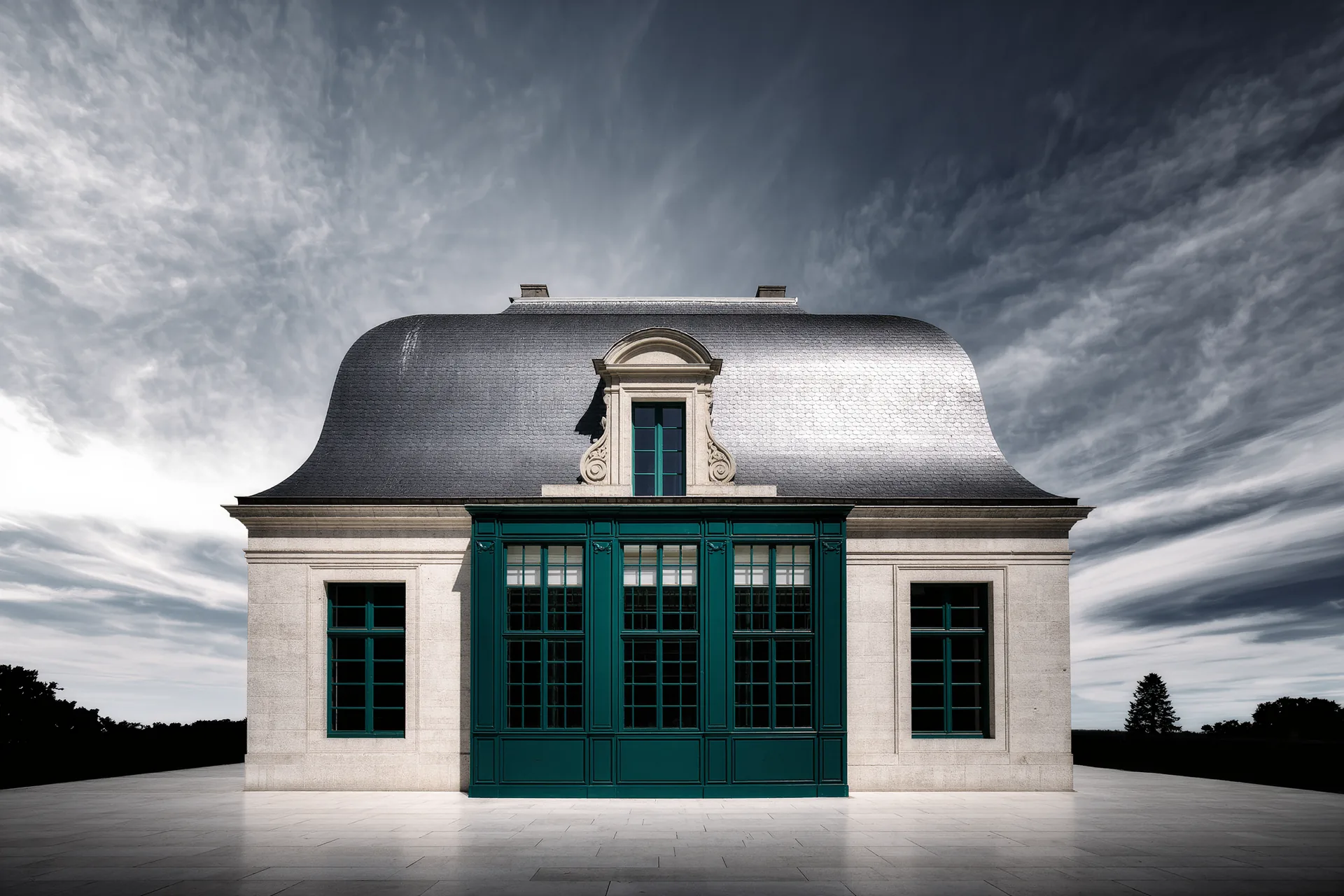Façade d'un château classé, toitures d'ardoise et fenêtres à meneaux, sous un ciel changeant.