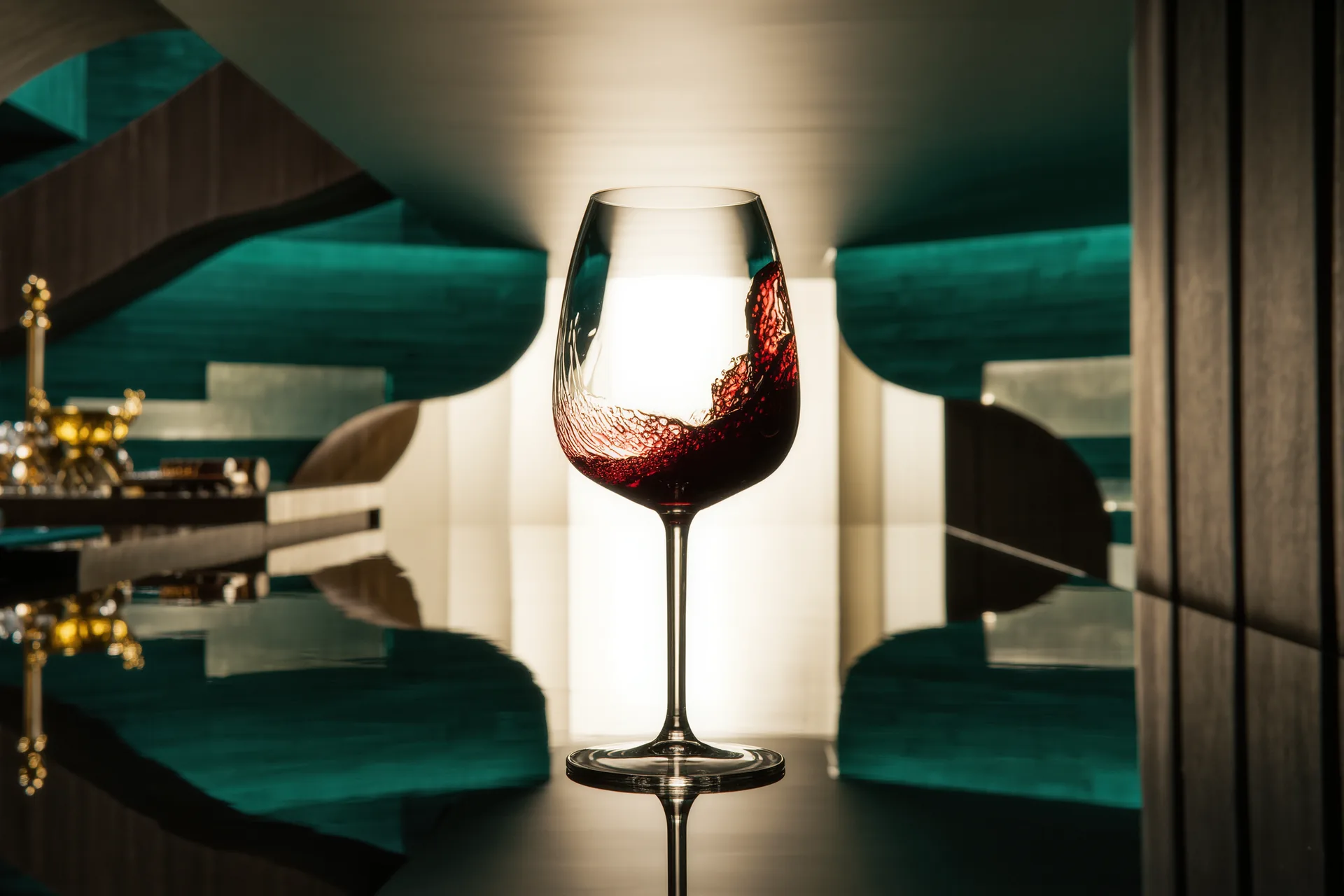 Verre de vin rouge légèrement trouble tenu à contre-jour dans un chai, reflets vifs et matière vivante