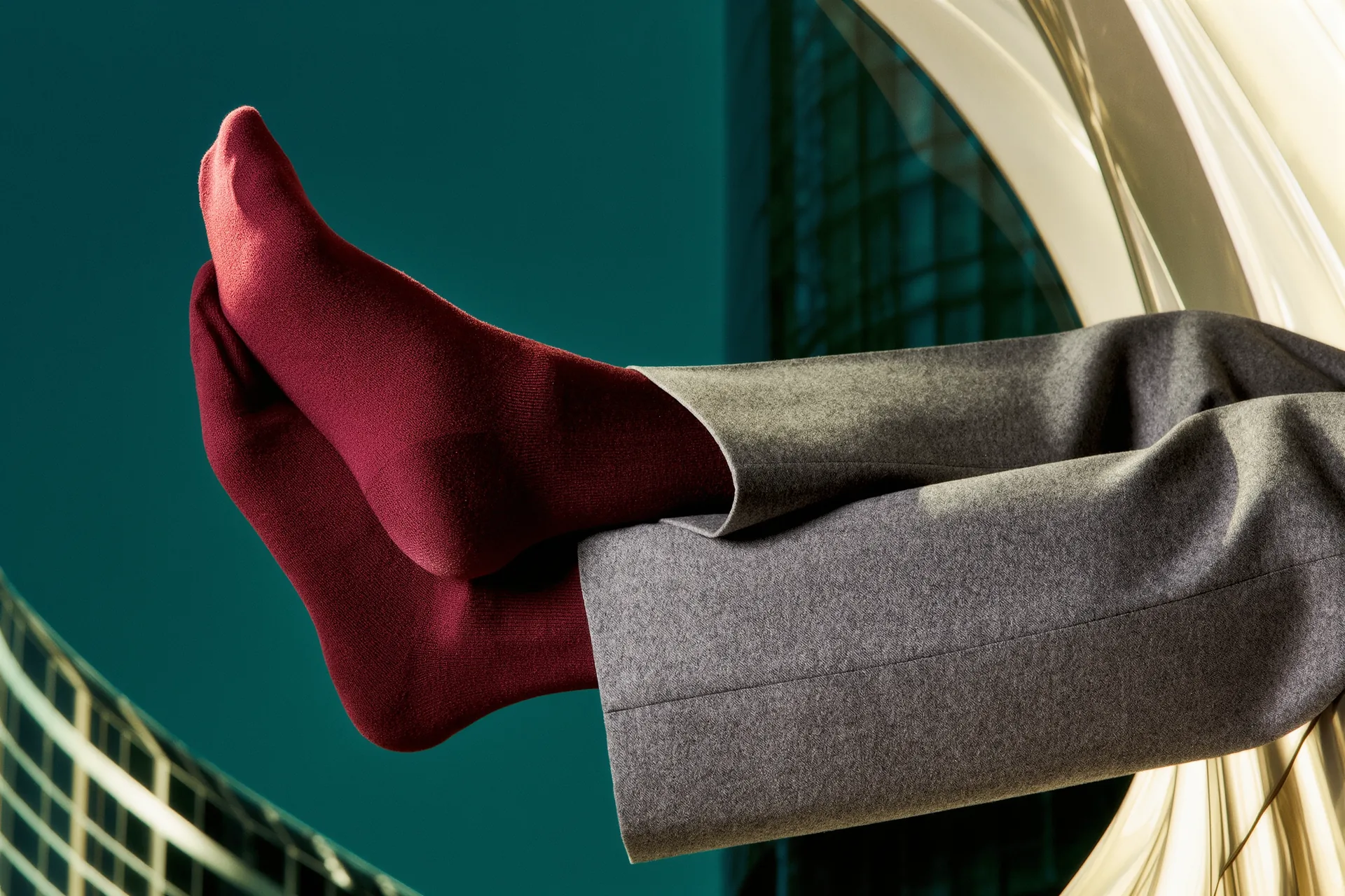 Une cheville en chaussette de fil d'Écosse bordeaux émergeant d'un pantalon de flanelle grise.