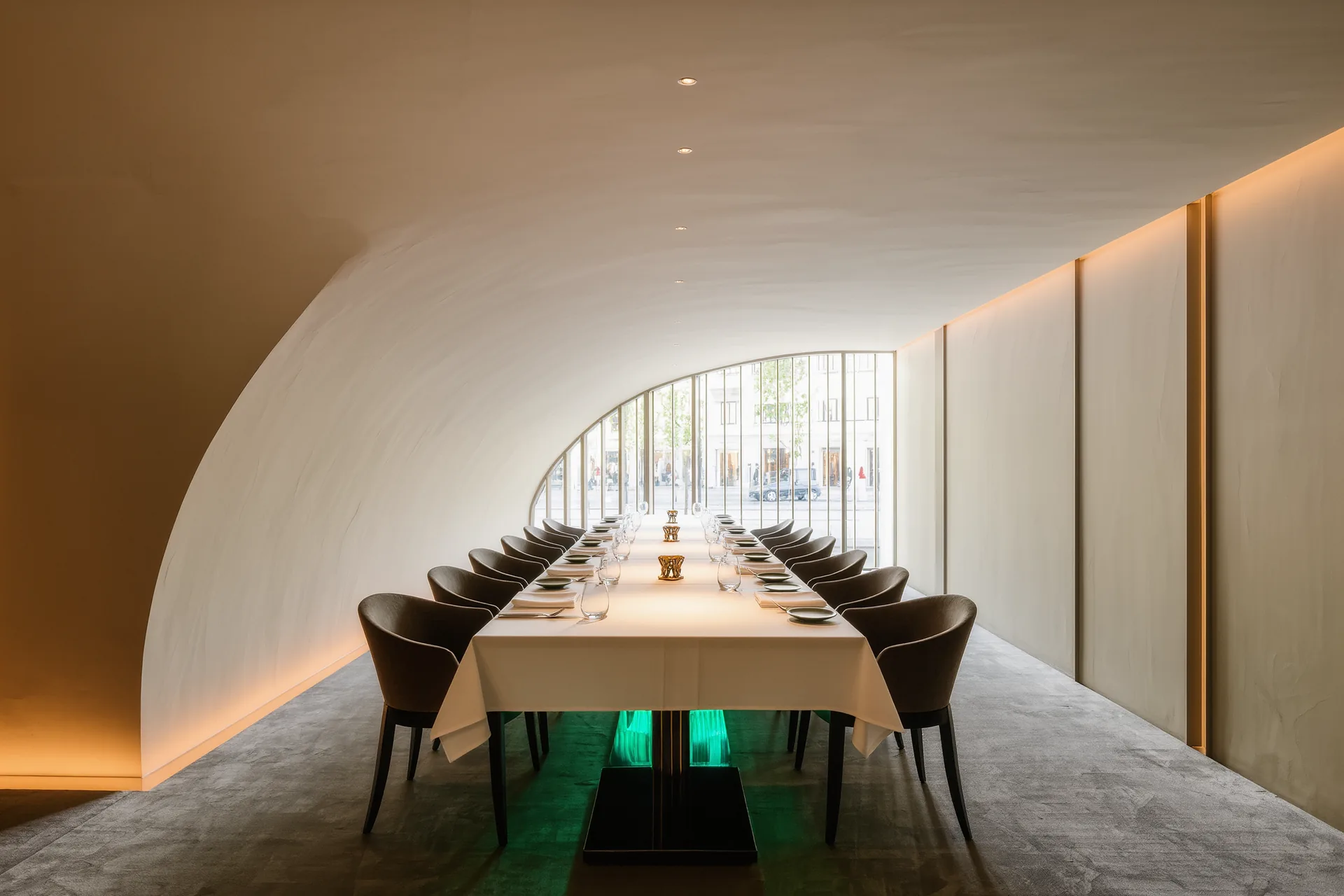 Table dressée près d'une fenêtre dans un restaurant du soir, nappe blanche et lumière chaude