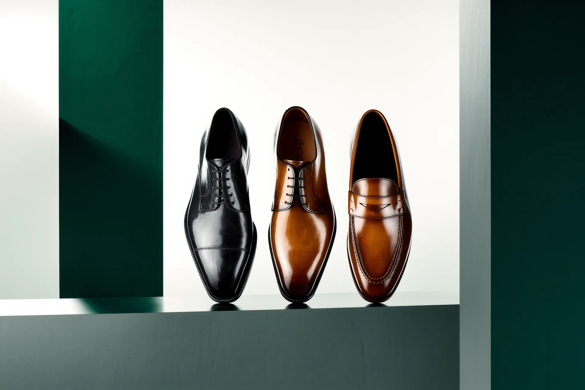 Trois paires de souliers en cuir patiné alignées : richelieu noir, derby marron et mocassin.