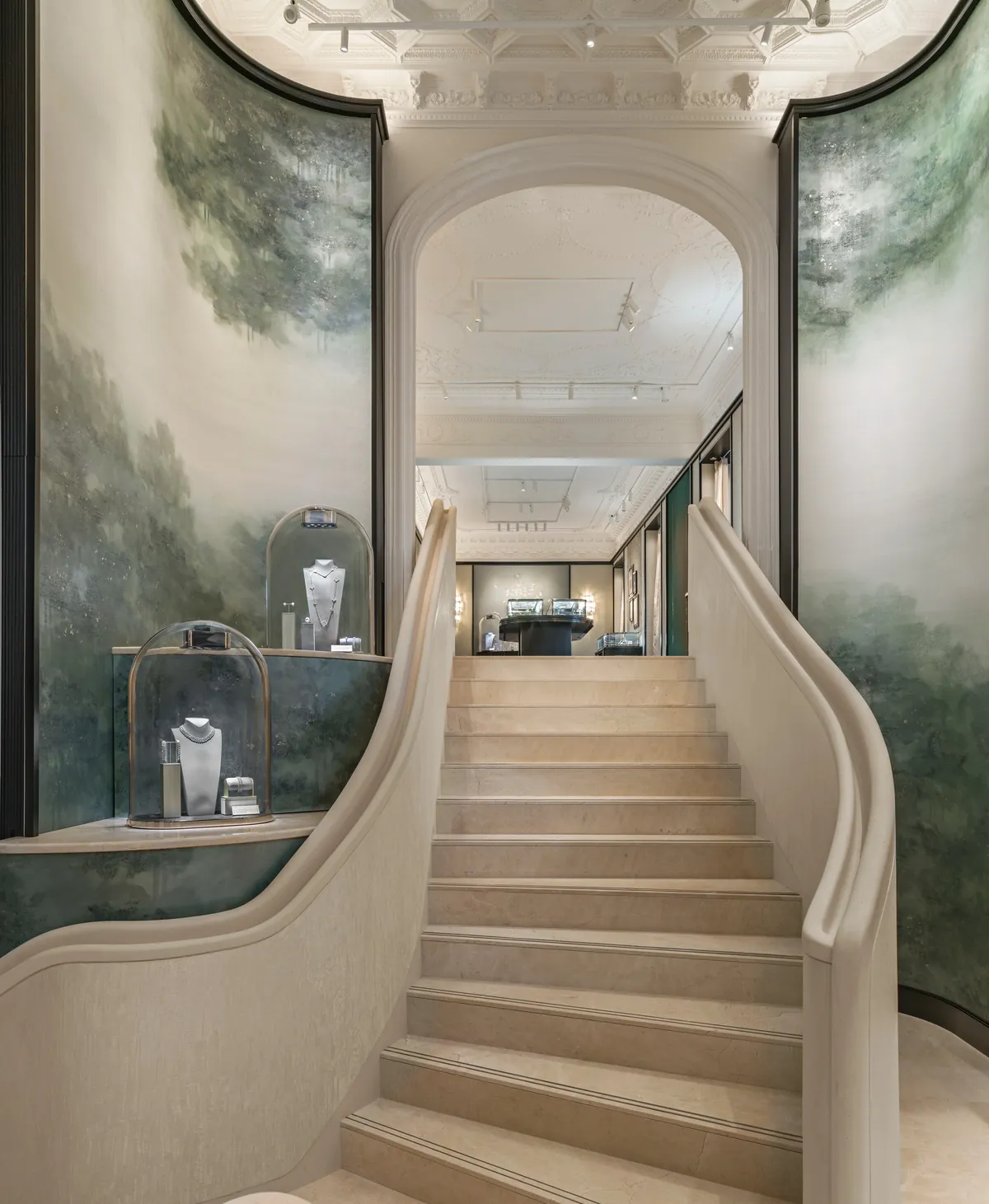 Escalier à la patine nacrée de la boutique Van Cleef & Arpels à Madrid, entre deux panneaux peints de paysages verts